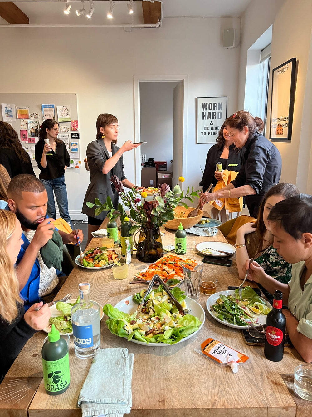 Friends around a long table sharing a meal with Graza squeeze bottles
